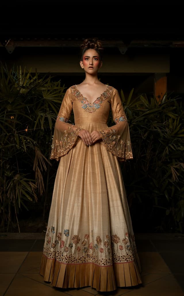 Woman in a floor-length golden ethnic gown with embroidered bell sleeves