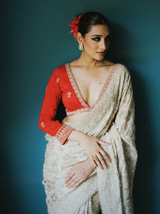 Woman in an ivory embroidered saree with a red designer blouse