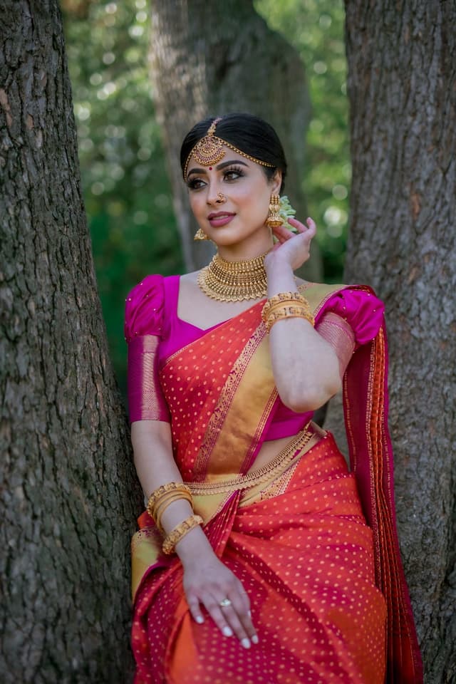 Woman in a pink and orange silk saree with gold jewellery