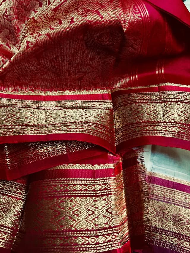 Close-up of gold zari borders on red silk sarees